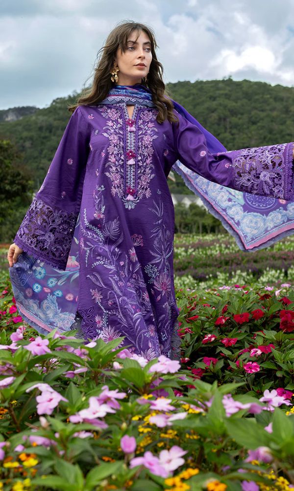 Woman in a purple embroidered dress standing in a garden with flowers and mountains in the background