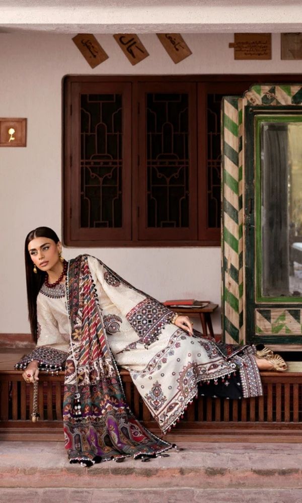 Model wearing a Jazmin Shahkaar cream-colored premium luxury lawn 3-piece suit featuring dark maroon and purple traditional geometric embroidery on wide-sleeves and pants, paired with a patterned multi-color digital print dupatta