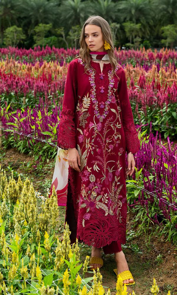 Woman in a burgundy embroidered outfit standing in a field of colorful flowers.